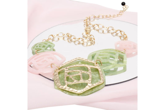 Necklace with green and pink floral pendants on a white background