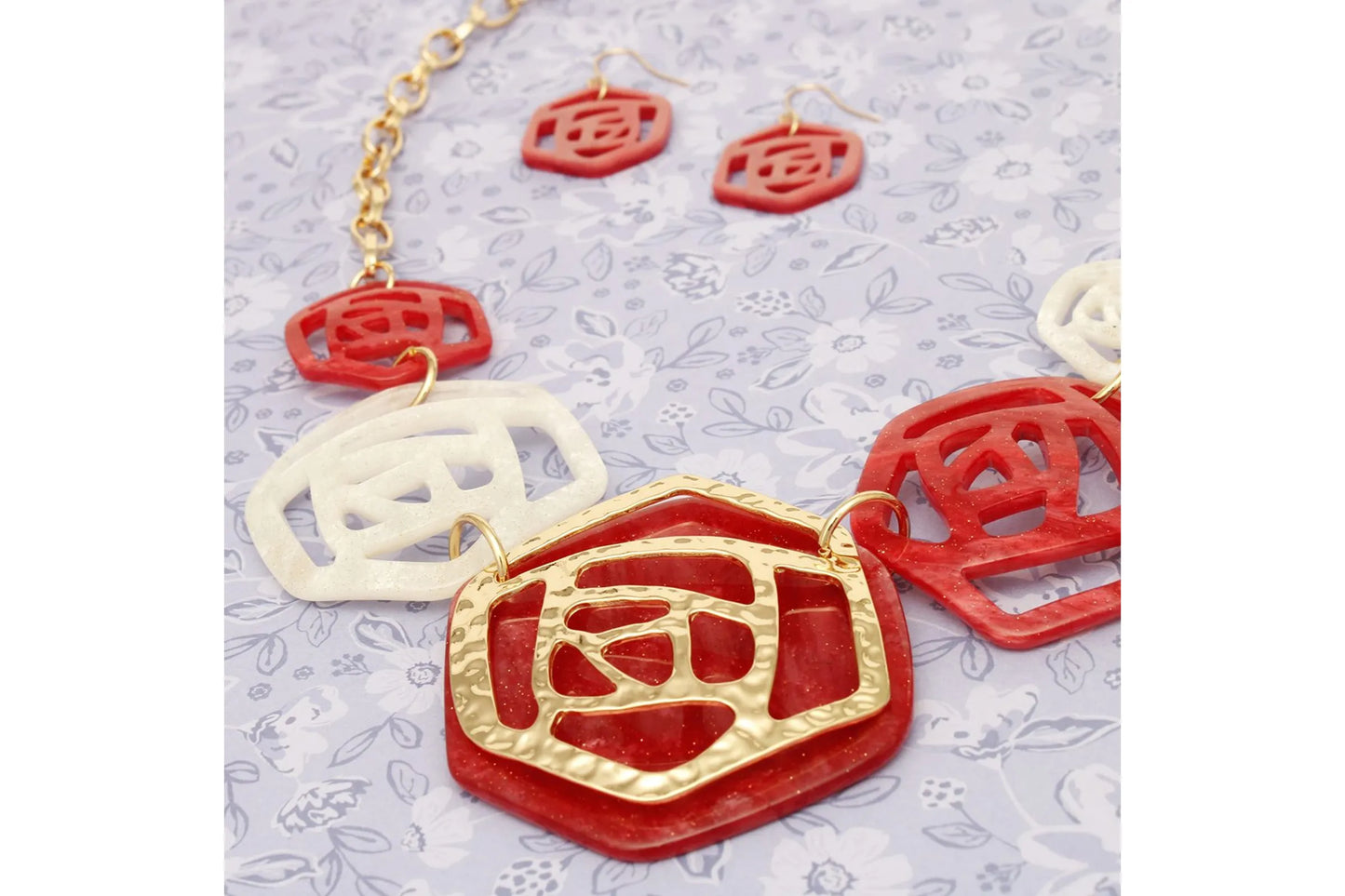 Jewelry set with red and gold necklace and earrings on a light gray background