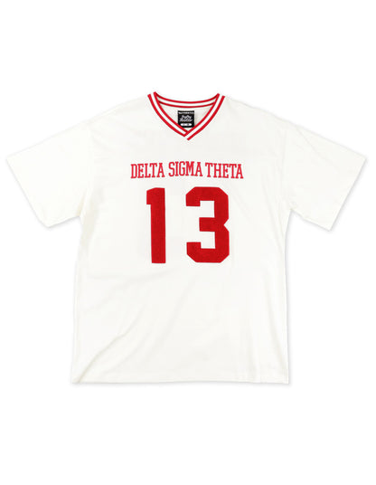 Front view of a white Delta Sigma Theta V-neck jersey t-shirt with red striped trim. The shirt features "DELTA SIGMA THETA" and the number "13" in red, varsity-style font.