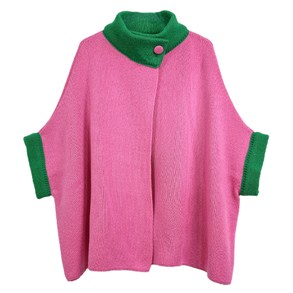 Flat lay view of a textured hot pink knit poncho cardigan featuring a contrasting emerald green high collar with a single button closure and matching green cuffs.
