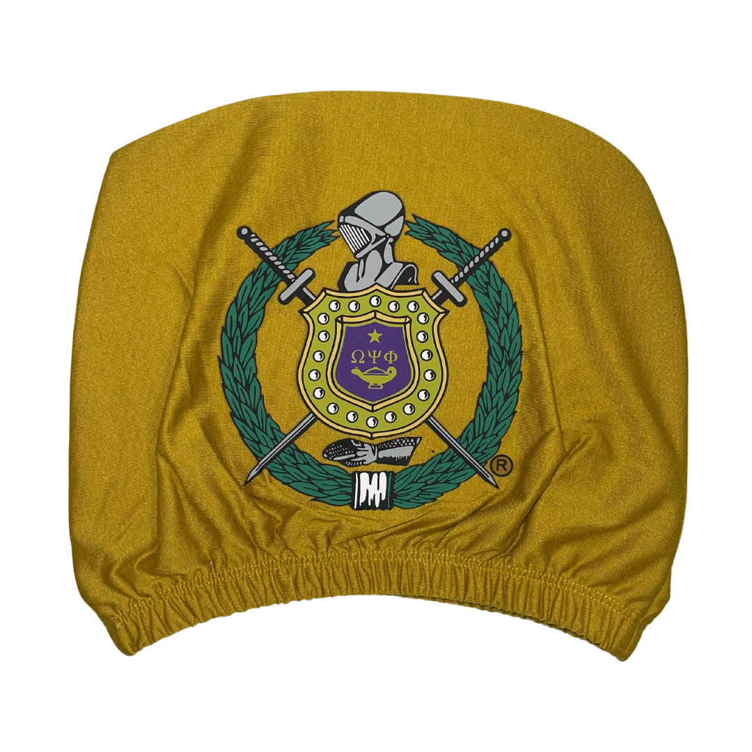 Omega Psi Phi gold car headrest cover with fraternity crest shield, swords, wreath, and knight's helmet on a gold background, featuring the Greek letters $\Omega\Psi\Phi$.Focus: Specific colors (gold), product type (car headrest cover), fraternity name/letters , and key emblem details (crest, shield, swords).