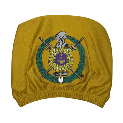 Omega Psi Phi gold car headrest cover with fraternity crest shield, swords, wreath, and knight's helmet on a gold background, featuring the Greek letters $\Omega\Psi\Phi$.Focus: Specific colors (gold), product type (car headrest cover), fraternity name/letters , and key emblem details (crest, shield, swords).